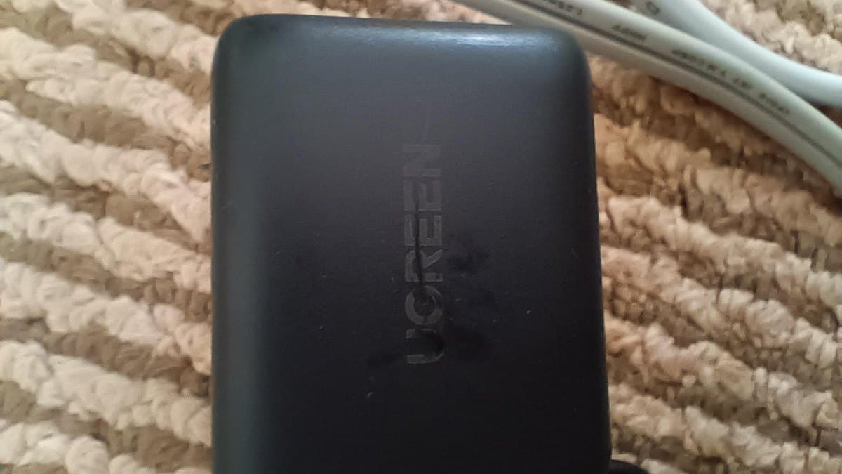 カーペットの上に置かれた黒い3口の充電器。白いケーブルが横にのびている